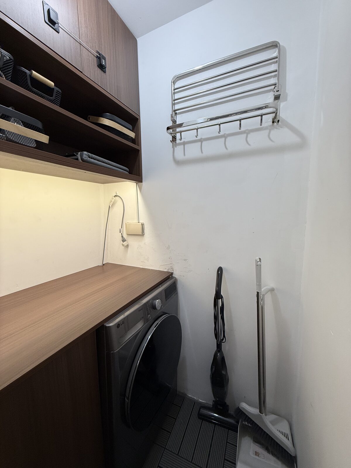 Service area with a front-load washer, folding counter and wall-mounted drying rack.
